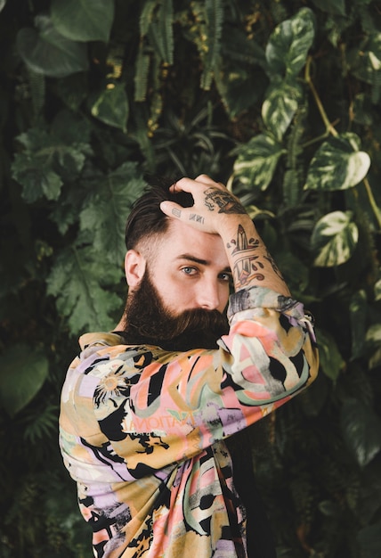 Portrait of a bearded young man with tattoo on his hand