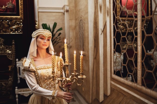 Princess in golden clothes carries candleholder with burning candles – Free Stock Photo Download