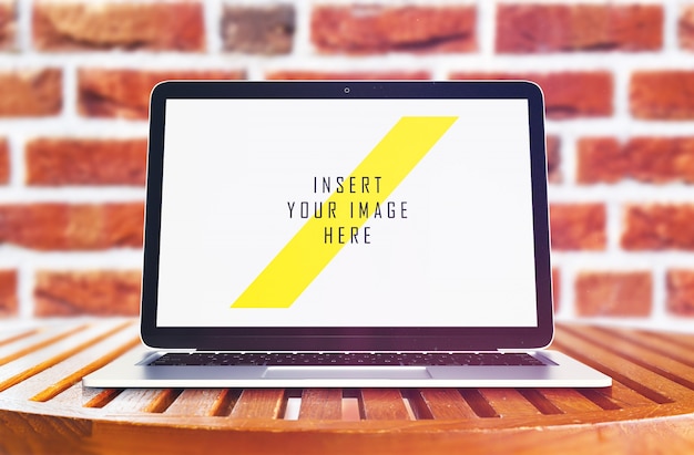 Laptop on wooden table in front of brick wall mock up – Free Stock Photo Download