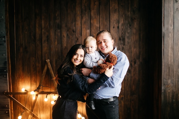 Happy smiling family at studio on background of the Christmas tree with gift