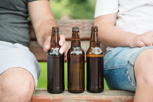 Crop men sitting on bench near beer – Free Stock Photo