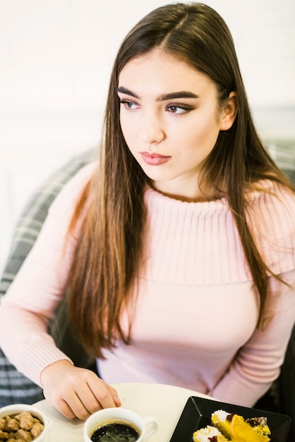 Beautiful young woman with coffee and desserts