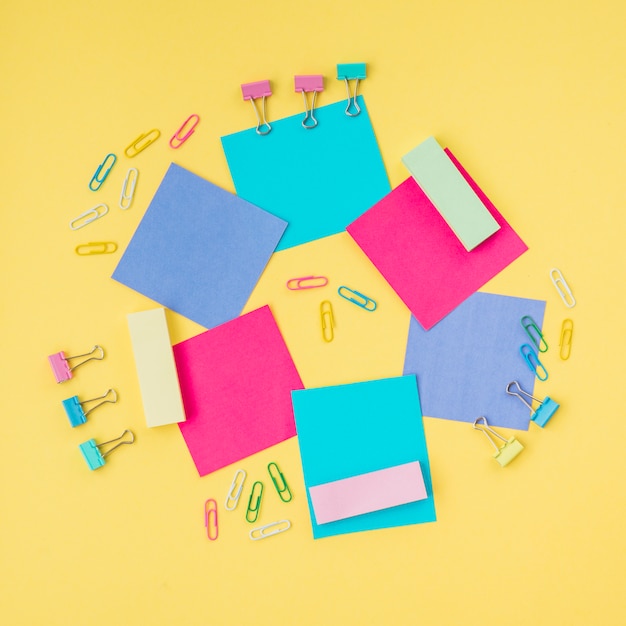 Multicolored Sticky Notes and Paper Clip on Yellow Surface