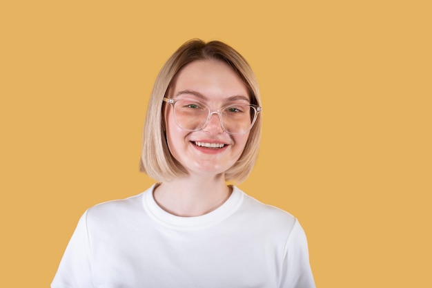 Young blonde woman smiling isolated on yellow