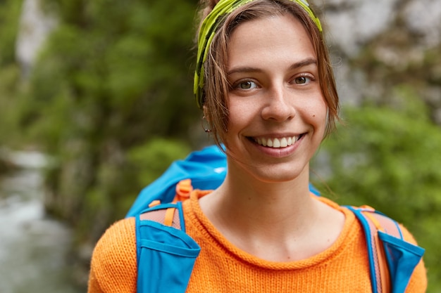 Cropped Image of Glad Female Smiling Gently on Hiking Tour with Rucksack