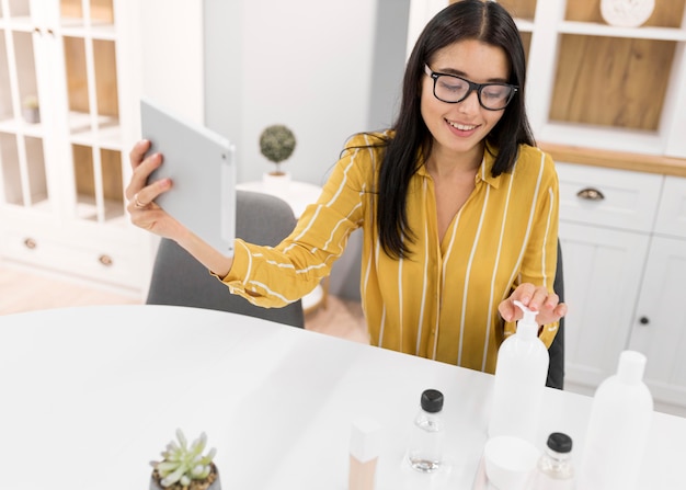 Female Vlogger at Home with Tablet and Products