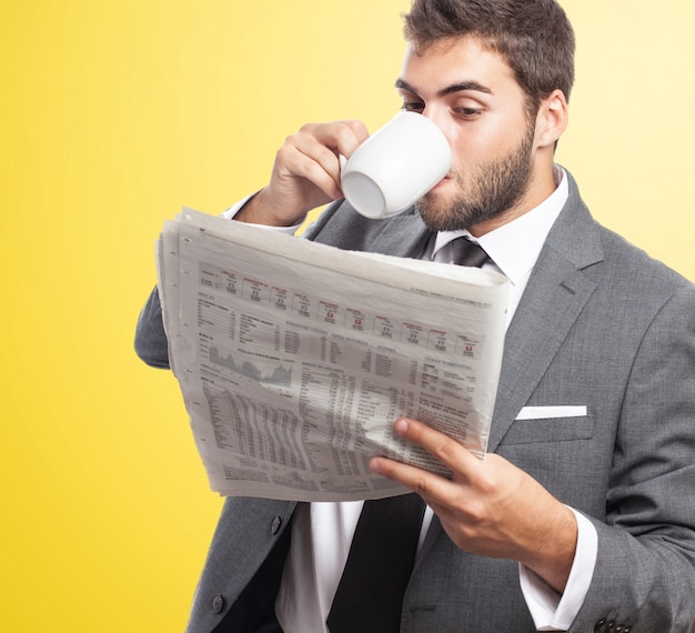 Employee drinking coffee while reading the newspaper