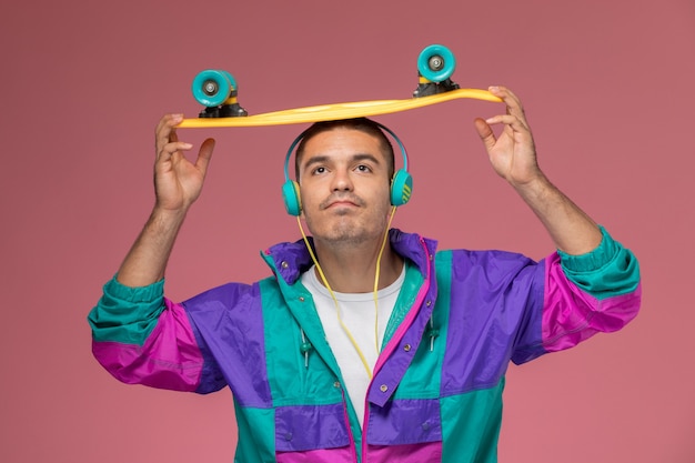 Front view young male in colorful coat listening to music on pink background