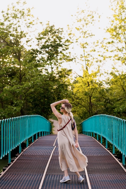 Beautiful blonde young woman in dress posing on bridge