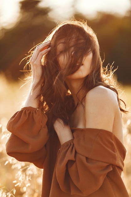 Woman in a summer field. Brunette in a brown sweater.