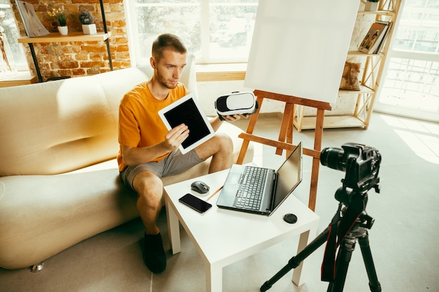 Caucasian male blogger recording video review of gadgets at home