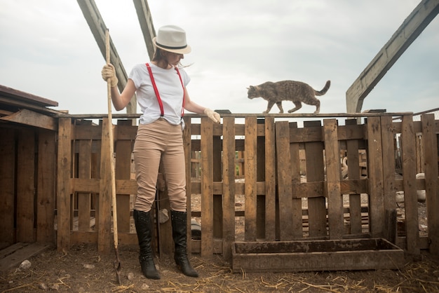 Farmer cleaning a henhouse with a cat