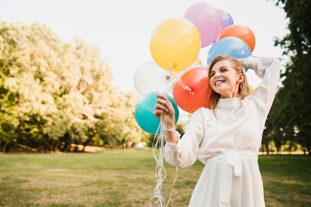 Smiley Girl in Park Holding Balloons – Free Stock Photo