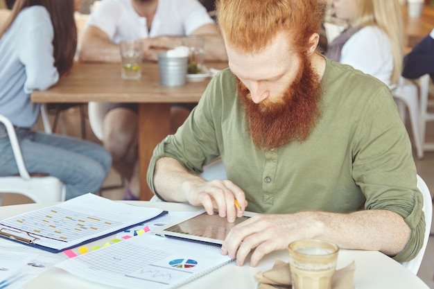 Young ginger man using tablet in cafe – Free Stock Photo