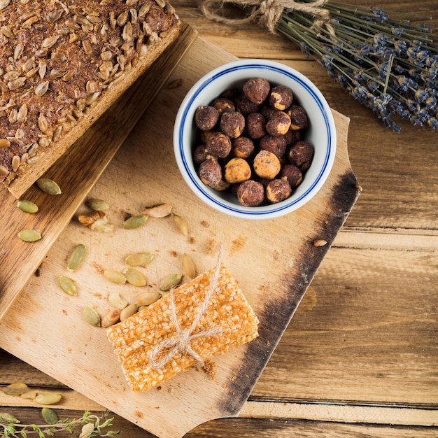 Overhead View of Hazelnut Bowl with Bread and Sesame Bar on Chopping Board