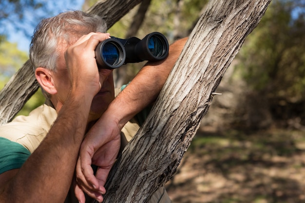 Man Looking Through Binocular by Tree