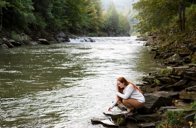 Full shot woman sitting by the river