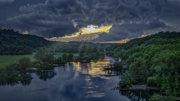 Breathtaking Sunset at a River in the Middle of a Green Forest Under the Dark Sky