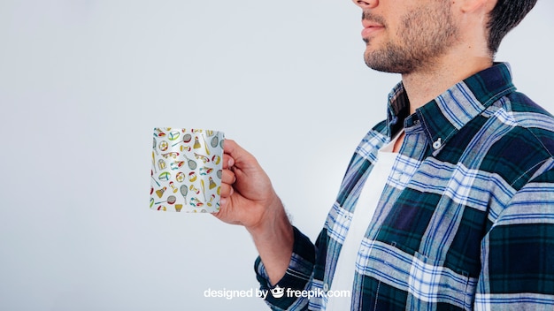 Young guy holding a coffee mug in a mockup design