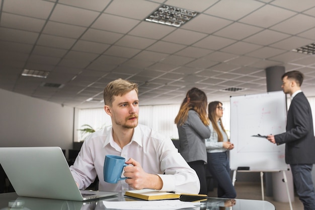 Businessman drinking coffee in office – Free Stock Photo