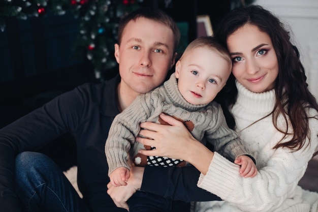 Family Christmas Eve: Beautiful mom, young dad and little baby sitting next to each other