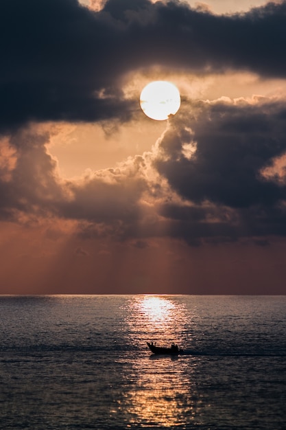 Vertical Shot of a Boat in a Sea at Sunset