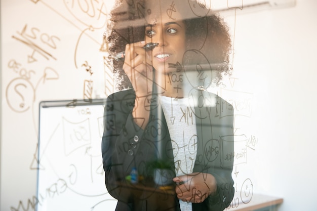 Young Businesswomen Writing on Glass Board