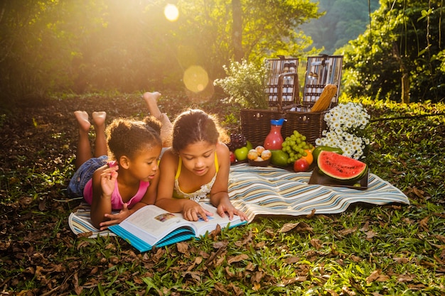 Sisters reading on picnic cloth