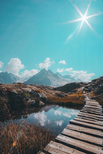 Wooden Passage Over Reflective Small Lake and Mountain Range – Free Stock Photo Download