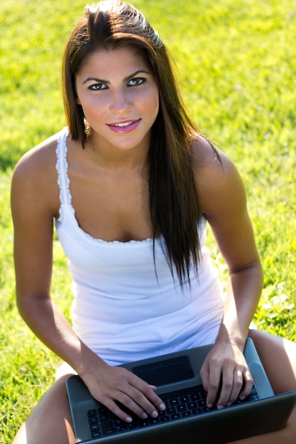 Woman with computer sitting on grass