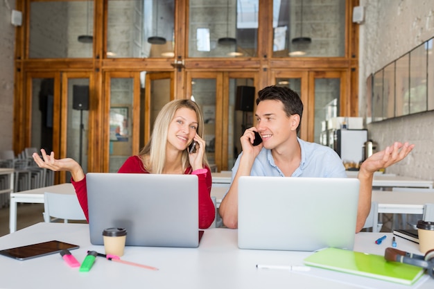 Young man and woman working on laptop in open space co-working office room