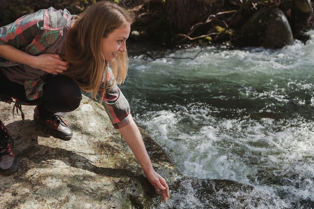 Happy woman touching water with her hand