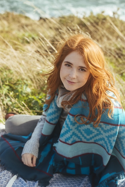 Smiling woman sitting on the shore with the sea – Free Stock Photo