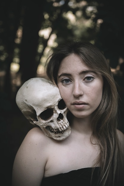 Beautiful female with skull in woods