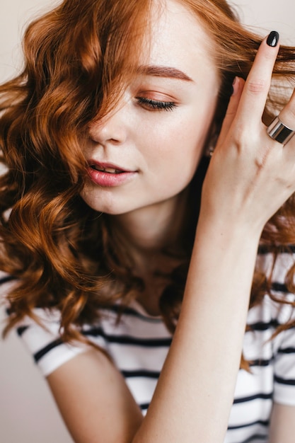 Close-up portrait of sensual ginger lady with brown makeup. Indoor photo of glad female model playing with her red wavy hair – Free Download