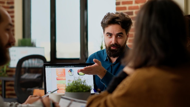 Project manager pointing at business charts on laptop