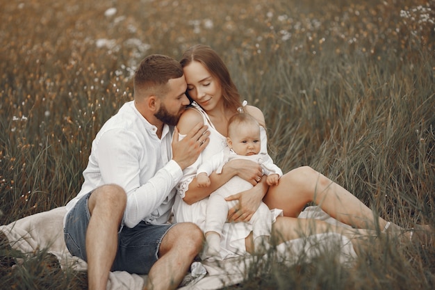 Family in a field with newborn girl and woman in a white dress