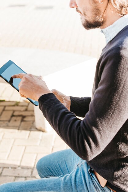 Close-up of man touching the touch screen of smart phone at outdoors