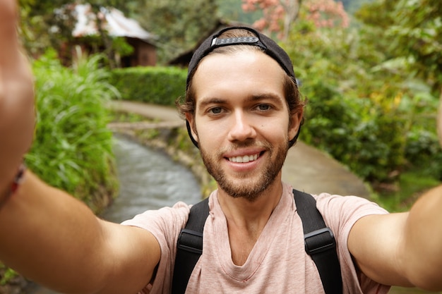 Close Up View of Happy Face of Attractive Hiker with Beard Smiling While Taking Selfie