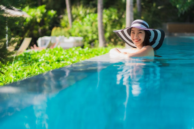 Portrait beautiful young asian woman happy smile in swimming pool around resort and hotel