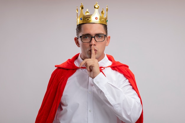 Super hero businessman wearing crown making silence gesture over white wall