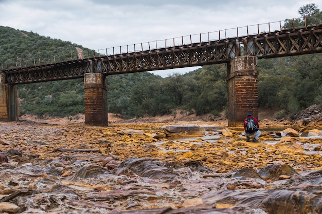 Young photographer capturing an old iron bridge over Rio Tinto