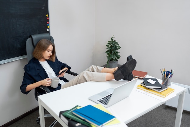 Full shot woman scrolling on phone at work