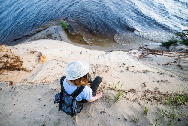 Woman Sitting on Sandy Cliff