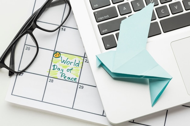 Top view of paper dove with laptop and world day of peace