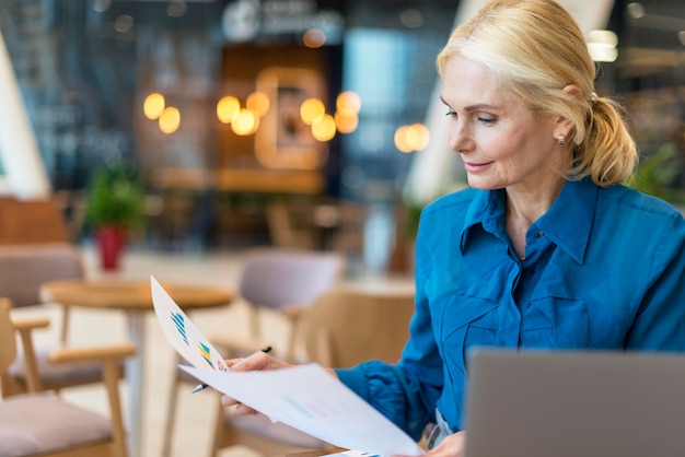 Front view of elder business woman working with papers and laptop