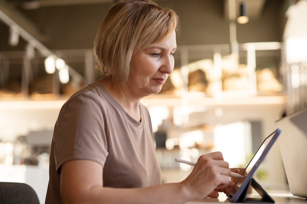 Senior woman working on her tablet at a cafe