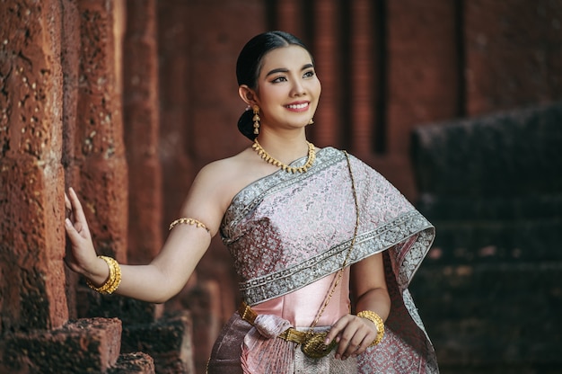 Charming Portrait of an Asian Woman in Traditional Thai Dress at a Historic Temple – Free Download