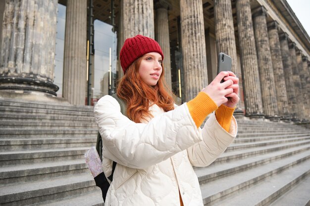 Redhead Female Blogger Capturing Sightseeing Moments on Smartphone – Free Download