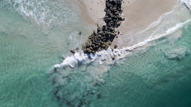 Aerial View of Ocean Waves Breaking on Beach Rocks – Free Download